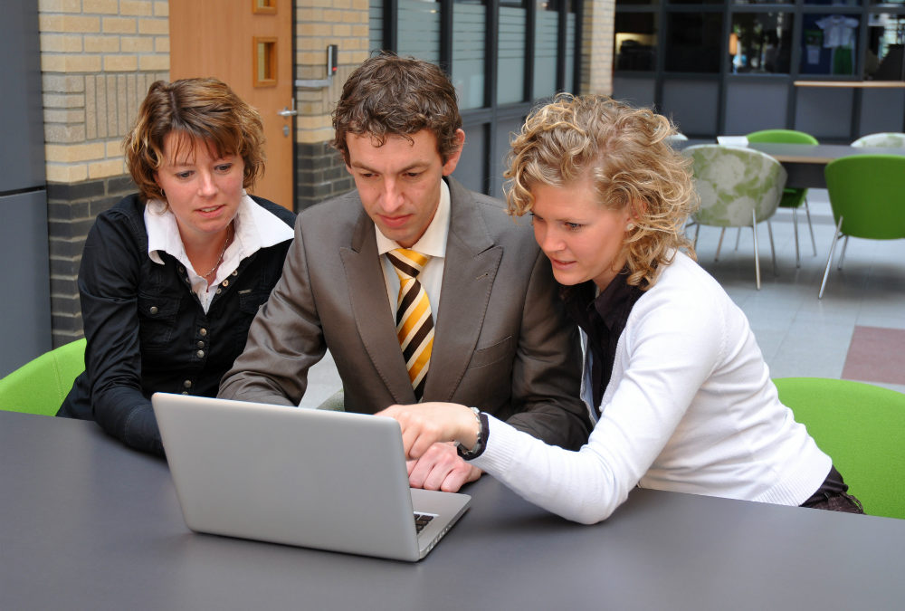 Three colleagues look at laptop at their small business